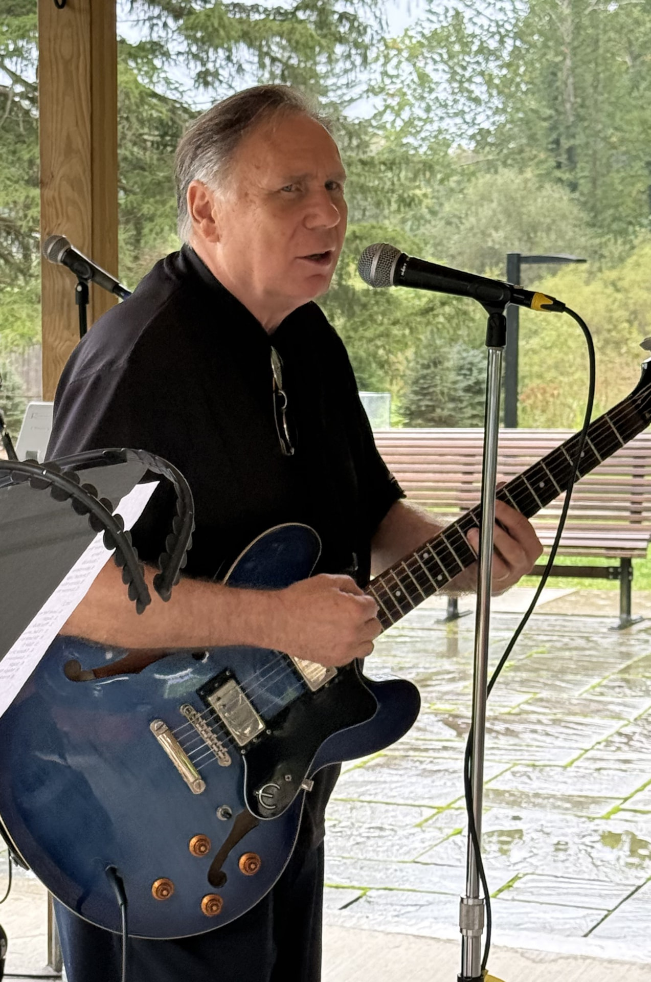Ed Perdian playing his blue semi-hollow guitar and singing into a microphone